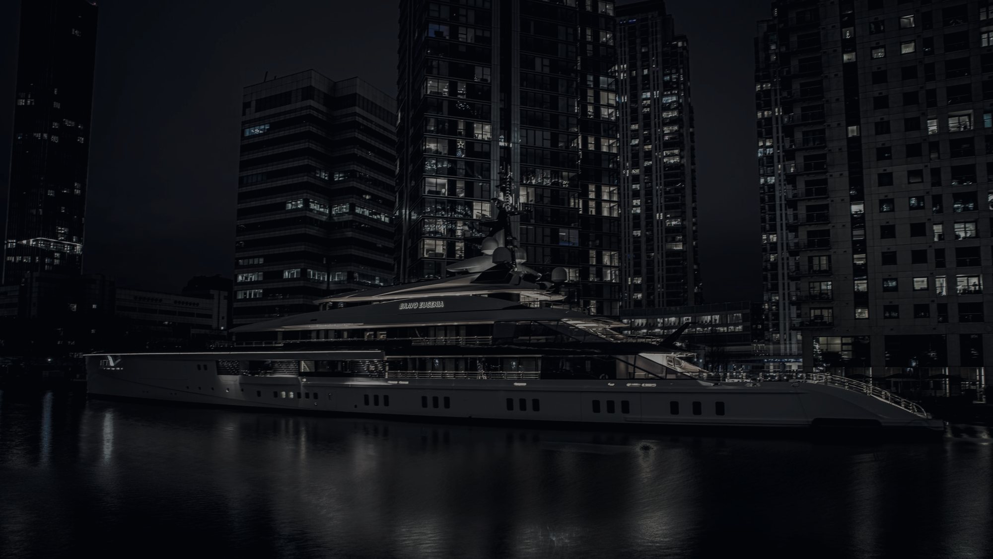 A superyacht moored against the towers of Canary Wharf at night